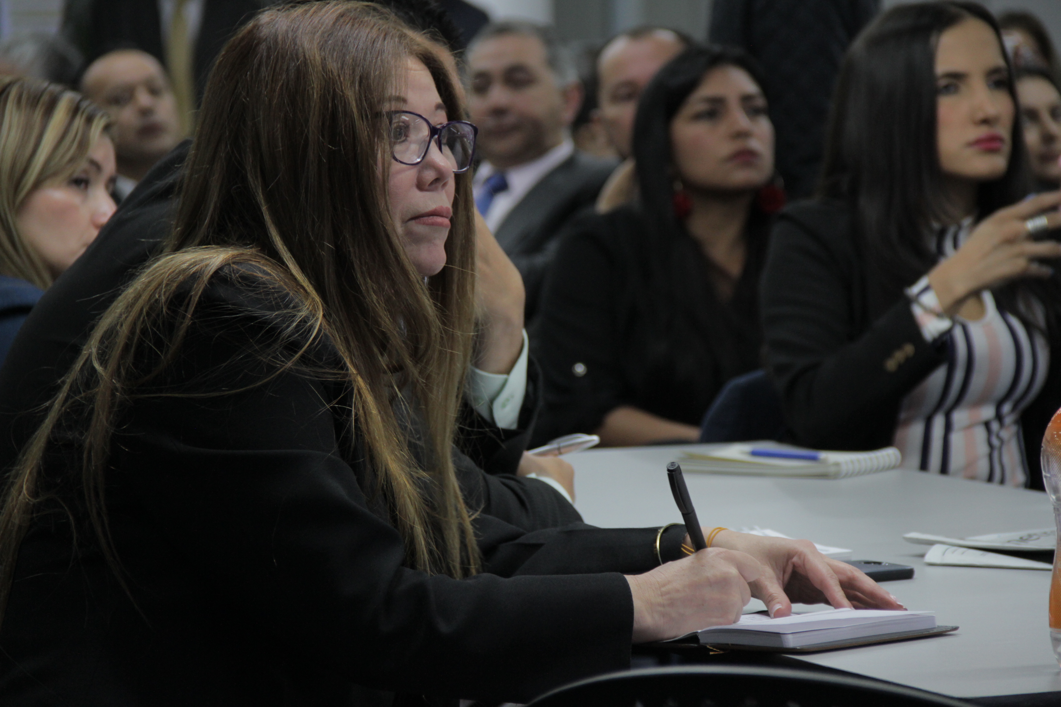 Mujer tomando apuntes y prestando atención en medio de una capacitación
