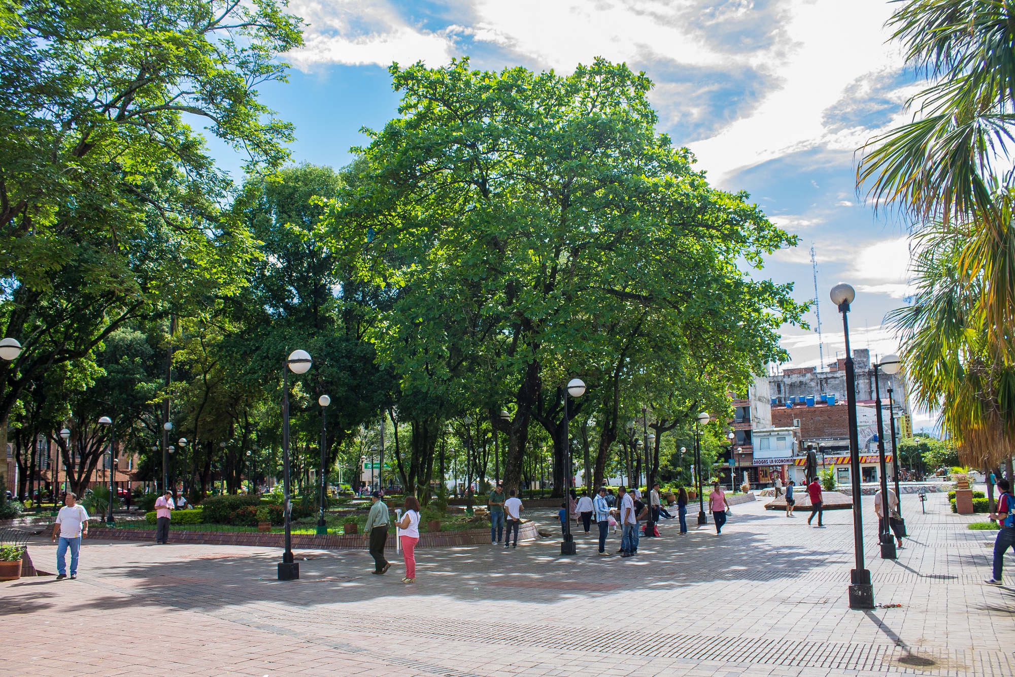 Imagen de una parque de un pueblo en donde se ven árboles y personas caminando