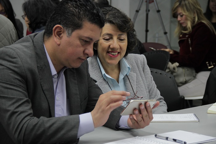 Hombre y mujer sentados mirando un celular