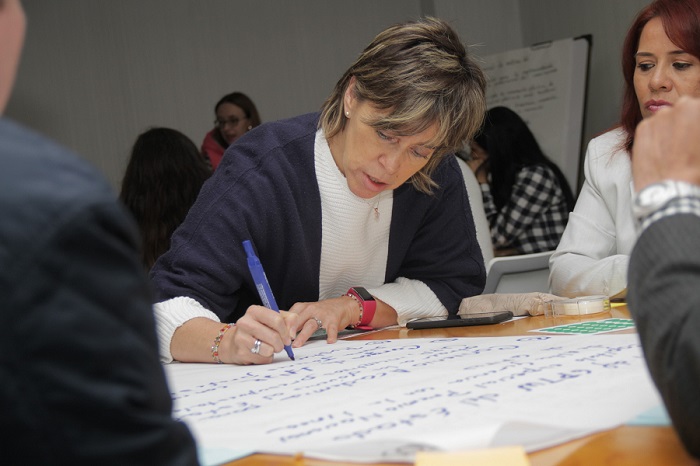 Mujer escribiendo en una cartelera sobre una mesa