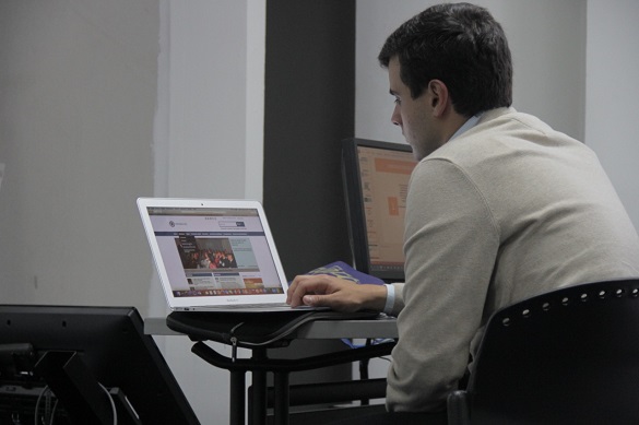 Joven sentado en una mesa trabajando en un computador