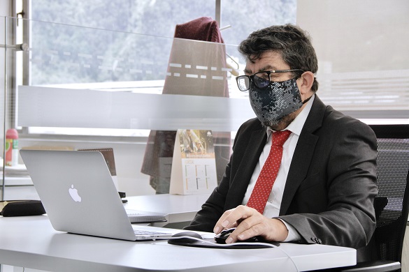 hombre con tapabocas sentado y trabajando en un computador portátil