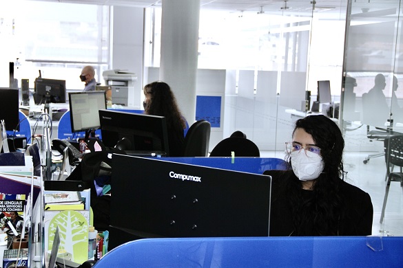 Tres personas con tapabocas trabajando en computadores