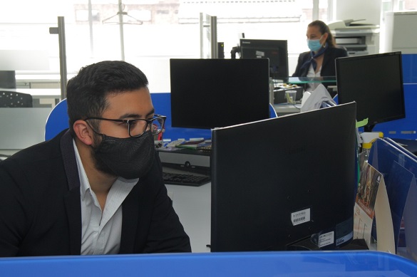 Imagen de hombre y mujer con tapabocas, trabajando en una oficina