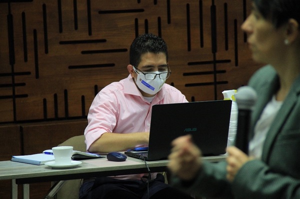 Hombre con tapabocas escribiendo en un computador portátil