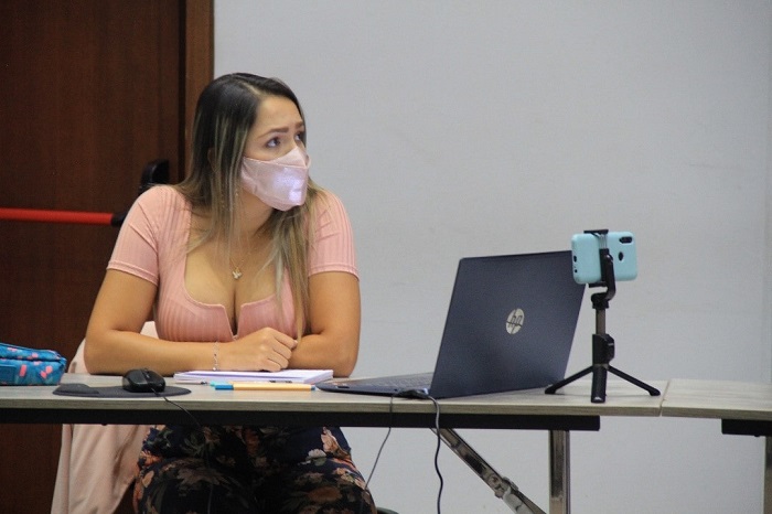 Mujer con tapabocas, sentada frente a un computador portátil 