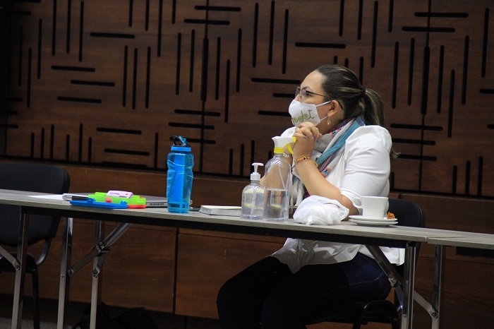 Mujer con tapabocas sentada en un silla frente a una mesa