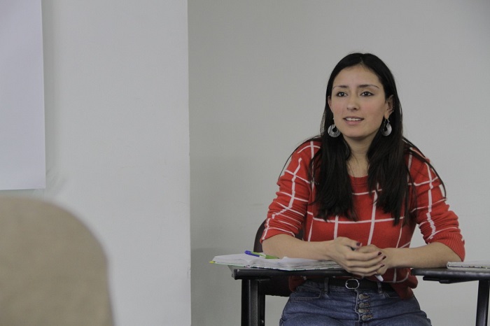 Mujer joven sonriente, sentada en un pupitre