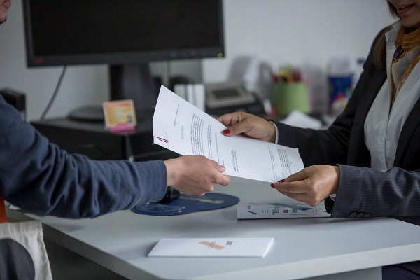 Manos de una mujer entregando un documento a las manos de un hombre