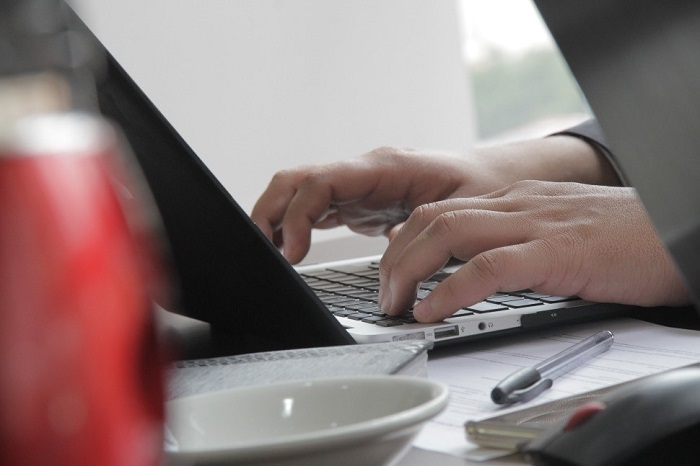 Manos de hombre sobre un teclado de un computador portátil