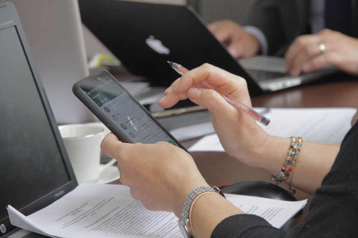 Se observan las manos de una mujer, en una mano sostiene un teléfono celular y en la otra un esfero