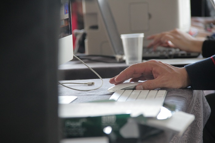 Mano de un hombre tomando un mouse frente al teclado de un computador