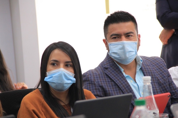 Hombre y mujer con tapabocas sentados uno junto al otro mirando de frente