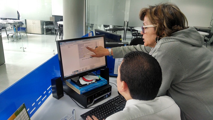 Una mujer y un hombre ven la pantalla de un computador 