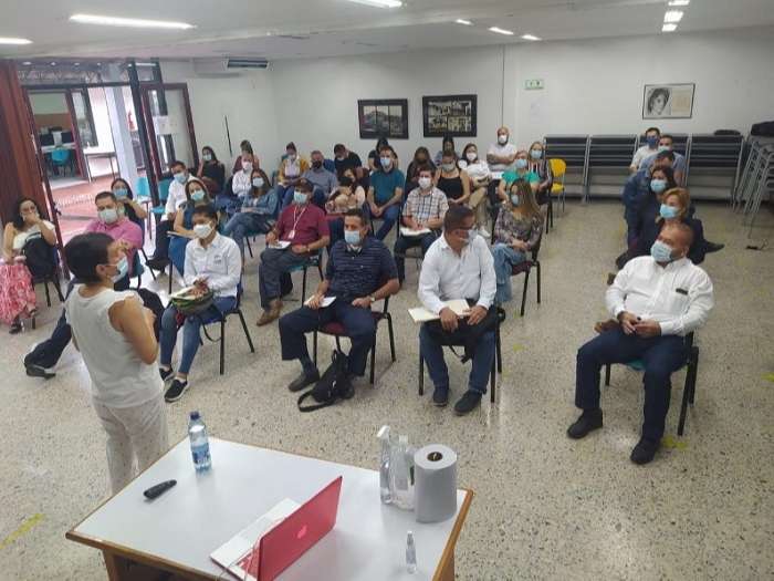 Mujer exponiendo frente a un grupo de personas sentadas en un auditorio