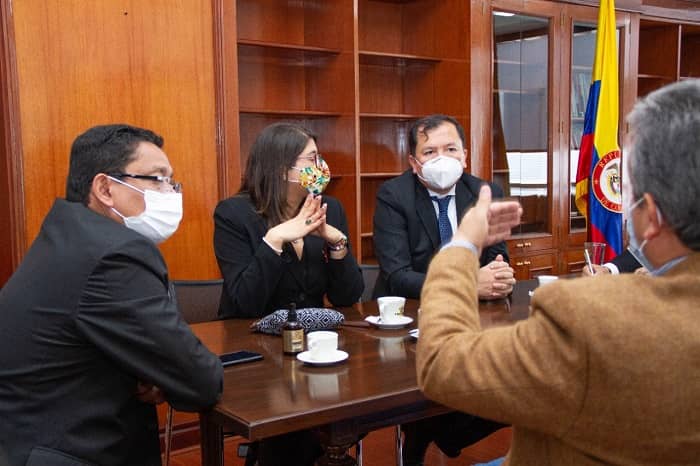 Cuatro personas interactuando en una mesa de reuniones
