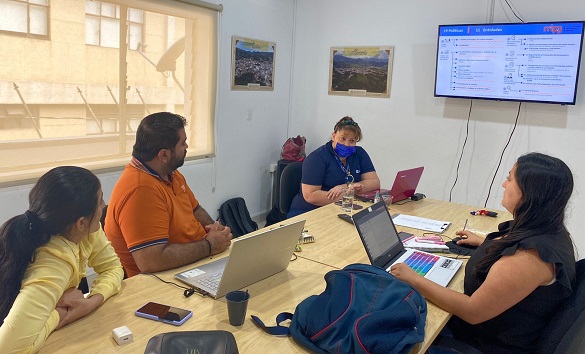 tres mujeres y un hombre sentados en torno a una mesa de reuniones