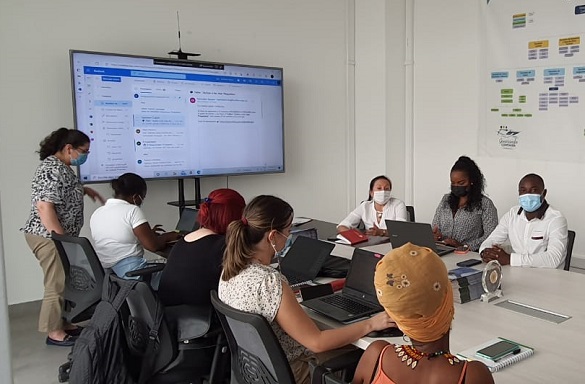 Una pantalla y una sala de reuniones con personas prestando atención a una exposicíón