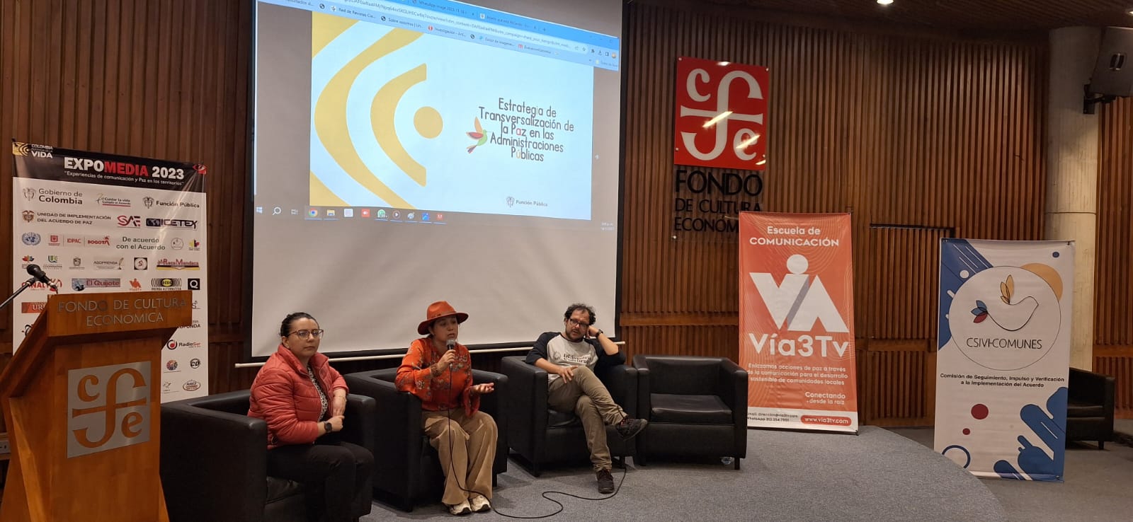 Persona conversando frente a un público en un panel de paz 