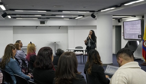 Realización del taller para prevenir y superar la estigmatización de personas en proceso de reincorporación, en el auditorio de Función Pública una mujer le habla a los participantes, seis mujeres y dos hombres escuchan,