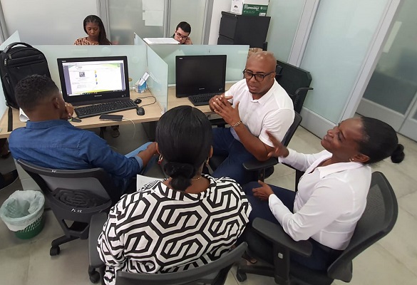 Cuatro personas, dos hombres, dos mujeres, sentados alrededor de un computador 