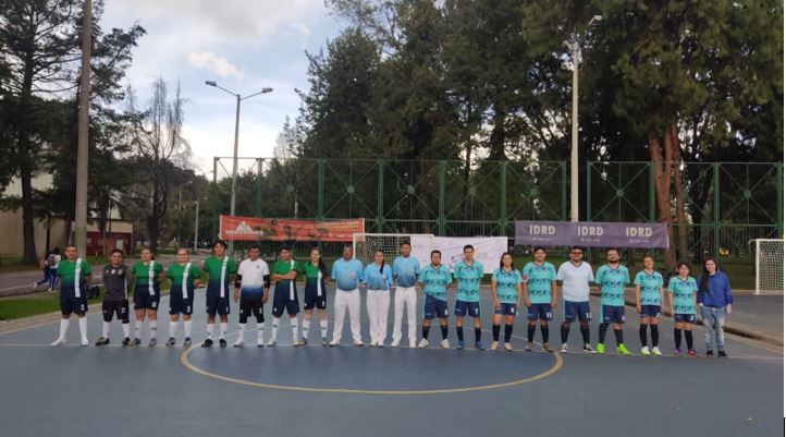 Integrantes de dos equipos de fútbol 8 formados en el centro de una cancha con los árbitros