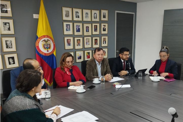 Seis personas, tres hombres y tres mujeres, sentados al rededor de una mesa de juntas