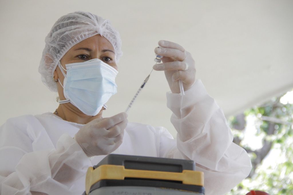 Enfermera sosteniendo jeringa y dosis de vacuna contra el COVID-19